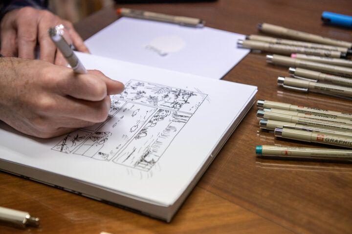 Deltagare som tuschar sina sidor utan att skissa med blyerts innan. Bredvid ritblocket ligger massor av tuschpennor.