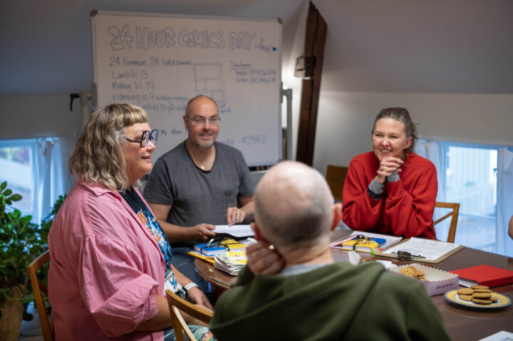 Samling vid lunch på söndagen för att berätta om serierna. Glada deltagare runt ett bord.